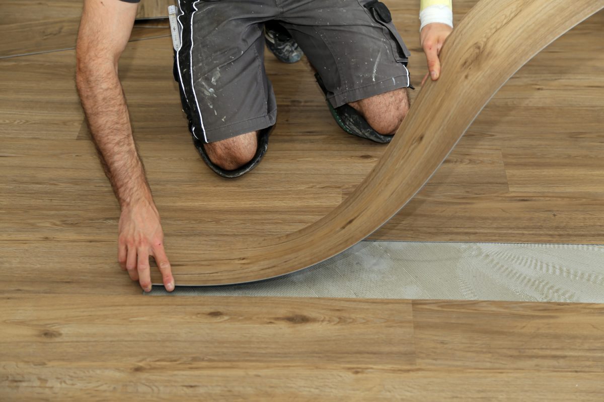 The worker installing new vinyl tile floor
