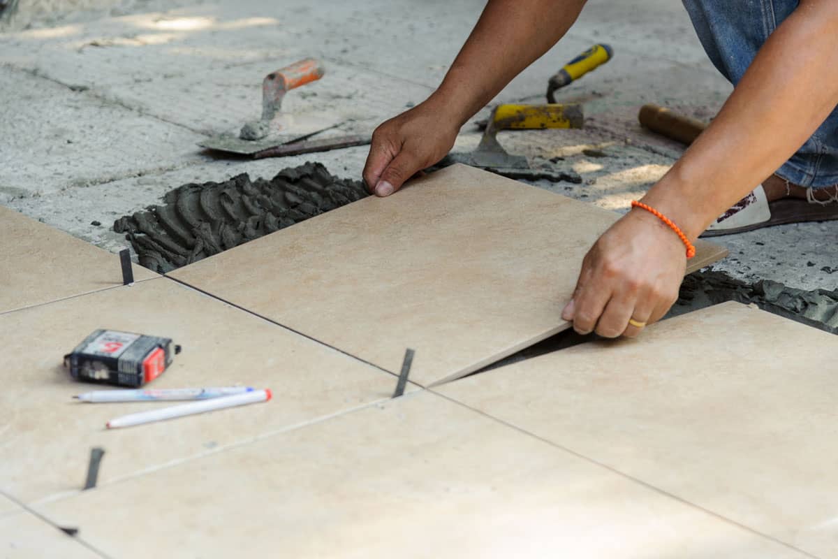 Tiler placing porcelain tile in position over adhesive on Floor tile installation
