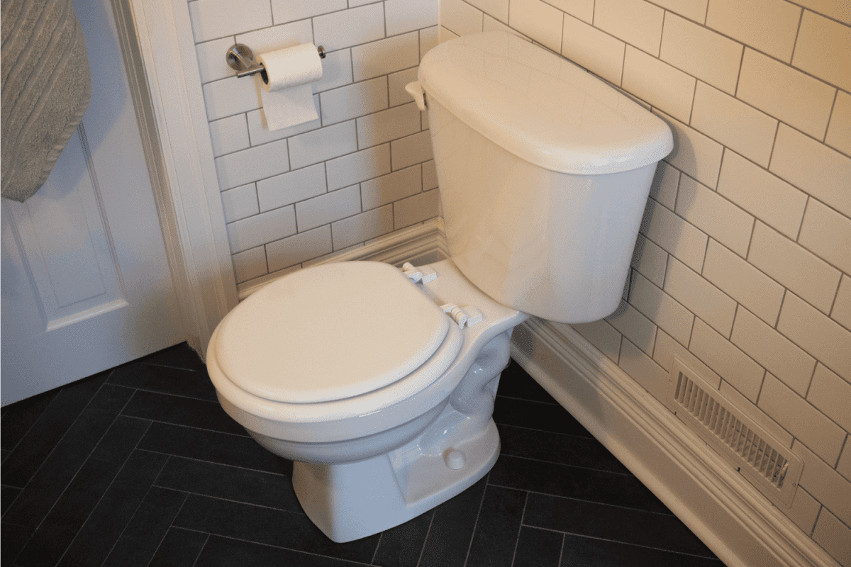 White toilet in contemporary bathroom. White subway tiles and charcoal gray herringbone floor tiles.