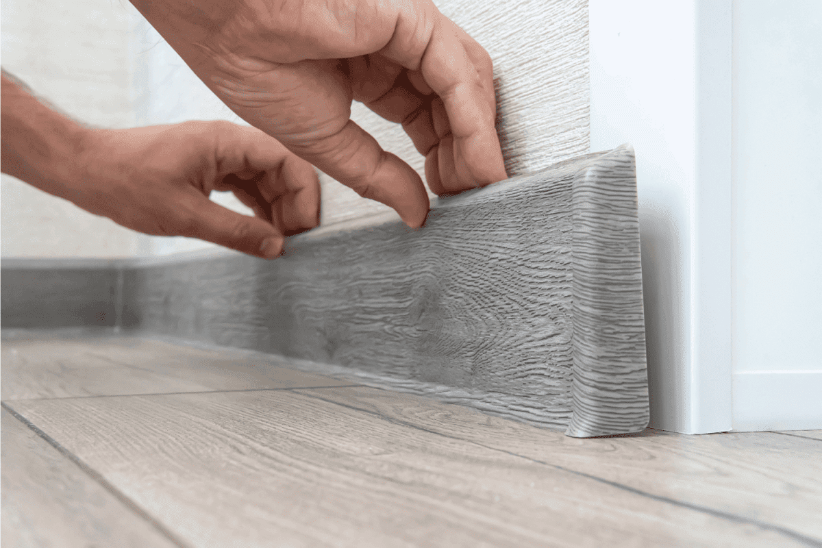 installing the floor skirting board. gray colored vinyl baseboard