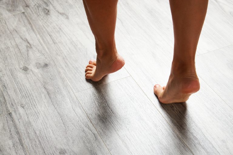 Female feet walking barefoot on clean wooden floor at home, Does All Laminate Flooring Sound Hollow?