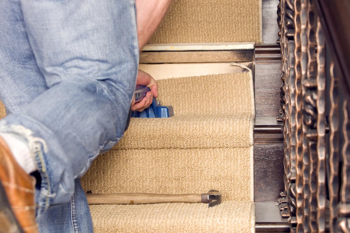 Installer using knee kicker to stretch stair carpet