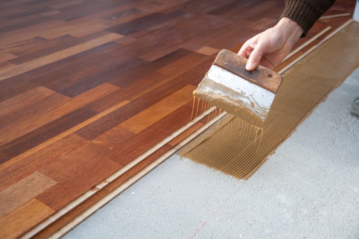 Laying hardwood floor. Spreading Adhesive - Apply sealant