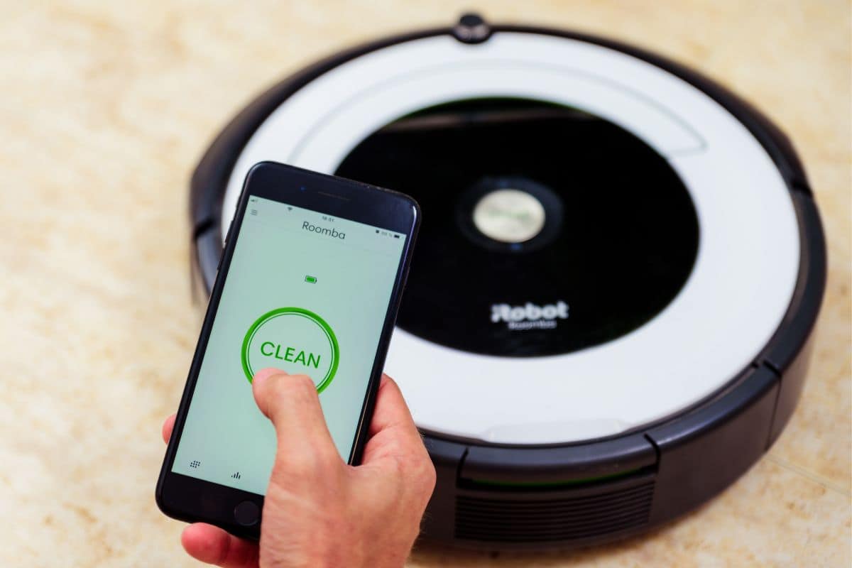 Man hand activating the roomba irobot vacuum cleaner from the application. Smart life concept, smart city, smart home.
