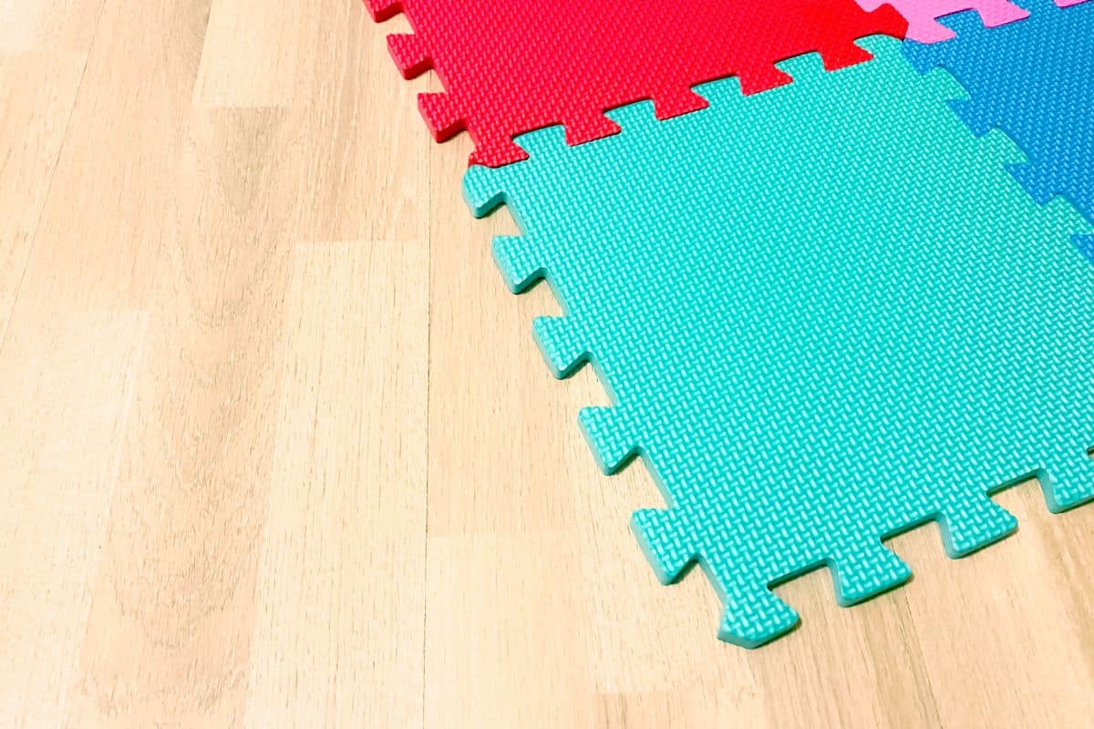 Soft rubber mat composed of colored blocks intersected with each other on a wooden floor — Photo
