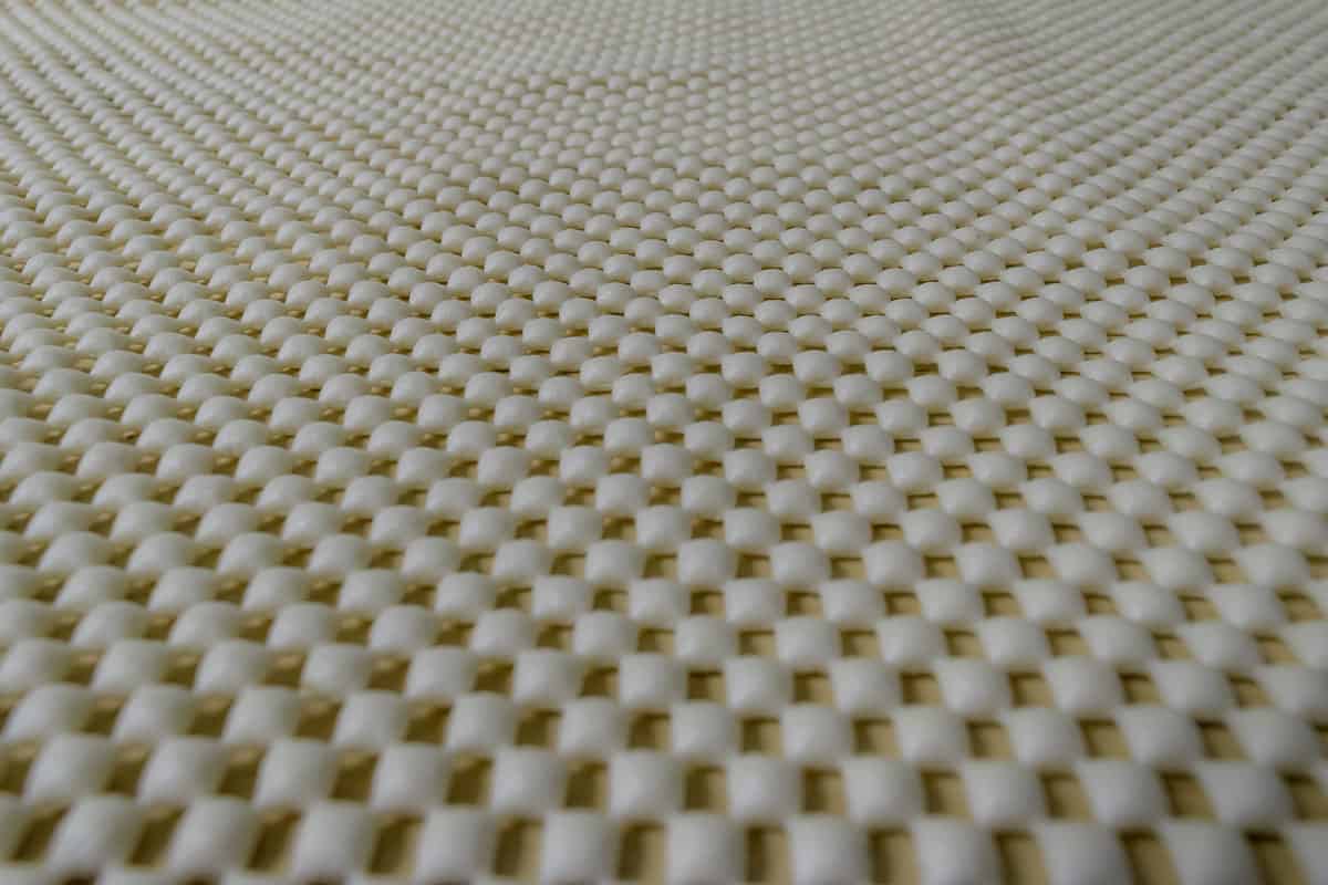 up close photo of a rug pad, non-slip rug pad, square shaped, checkered, color dirty white