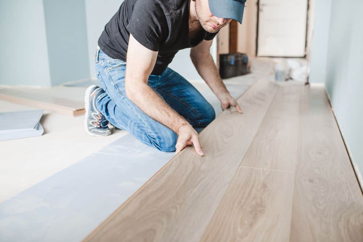 Close-up of the work of a master floating flooring installation - installing laminate on the floor - male hands during work.