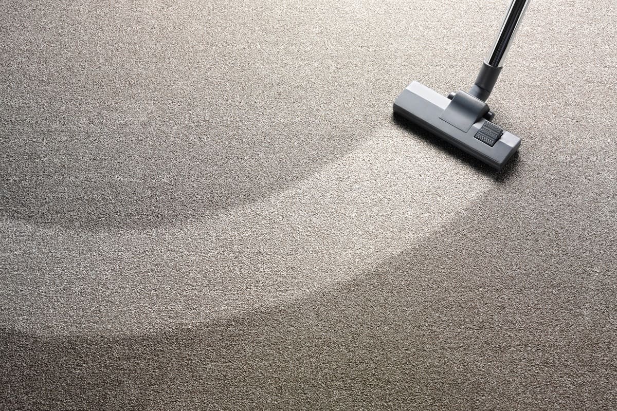 How Often to Clean a Carpet - Vacuum cleaner on a carpet with an extra clean strip for copy space