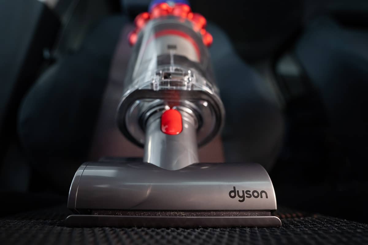 What Are The Common Issues Of Dyson Stick Vacuums - Dyson Cyclone V10 Fluffy vacuum cleaner on car seats with car interior background. Ready for cleaning.