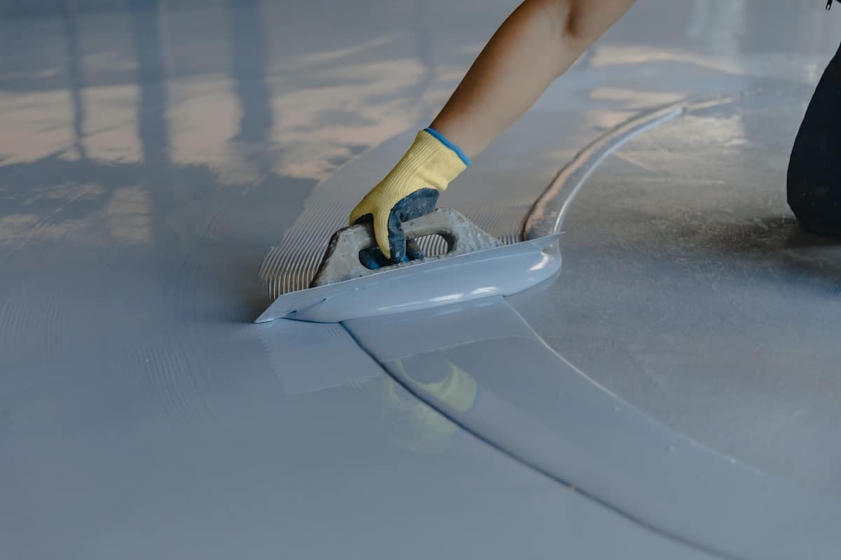 Will Garage Floor Epoxy Stick To Wood - The worker applies gray epoxy resin to the new floor