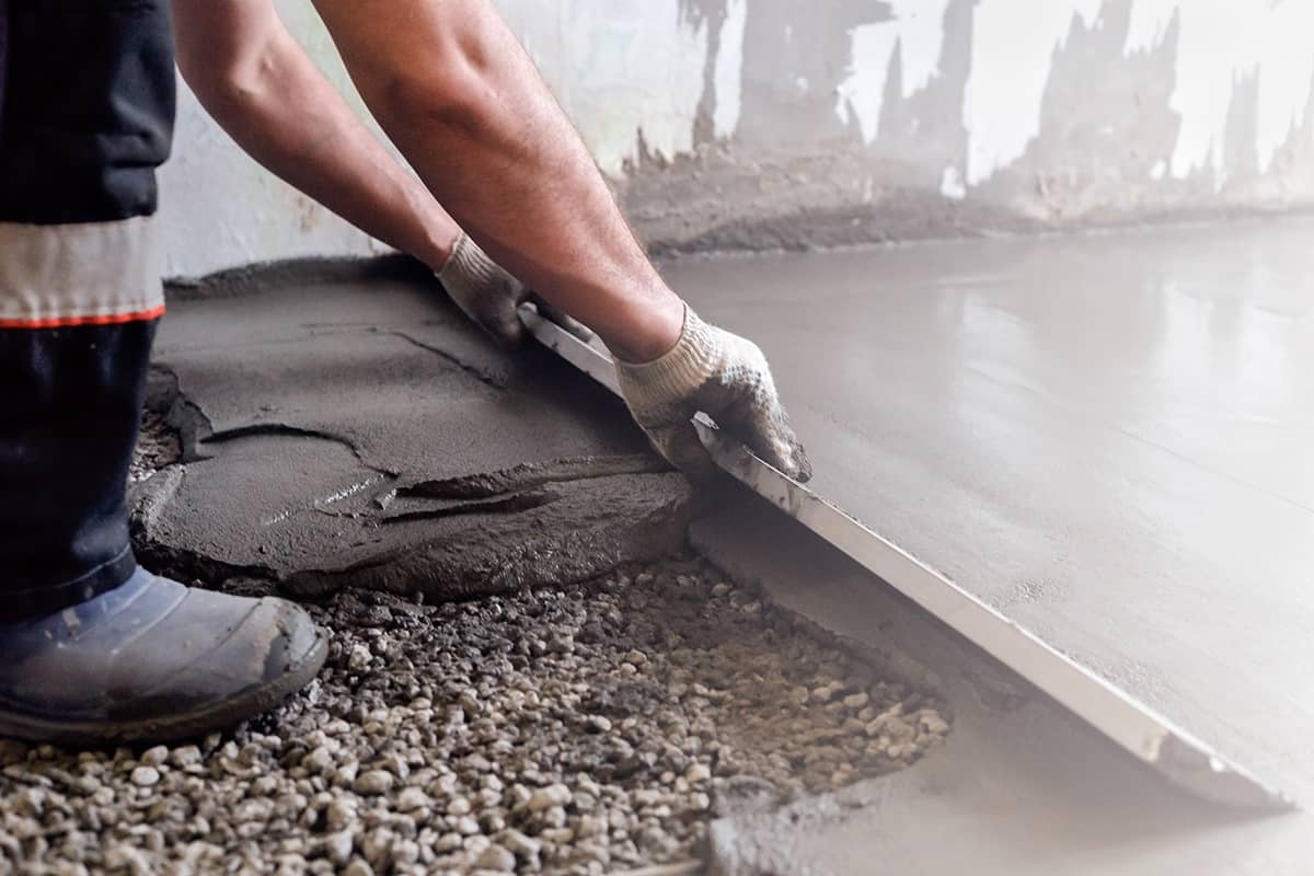 Worker levels a floor cement mortar