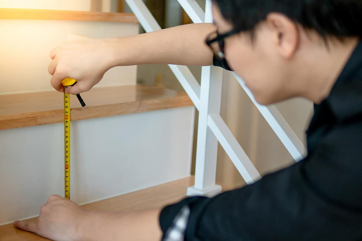 Worker using tape measure for measuring stair