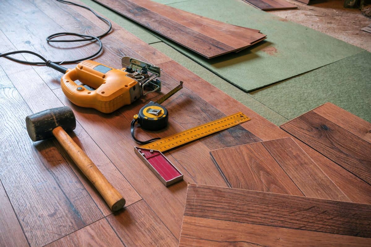 different carpenter tools (rubber hammer, electrofret, joiner angle) on the laminated floor