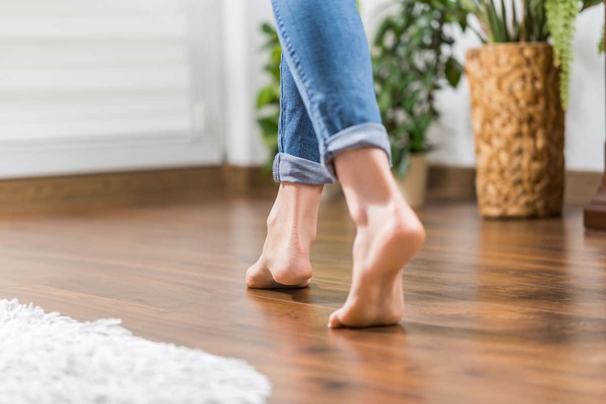 photo of a woman feet on the wood floor tile of the living room