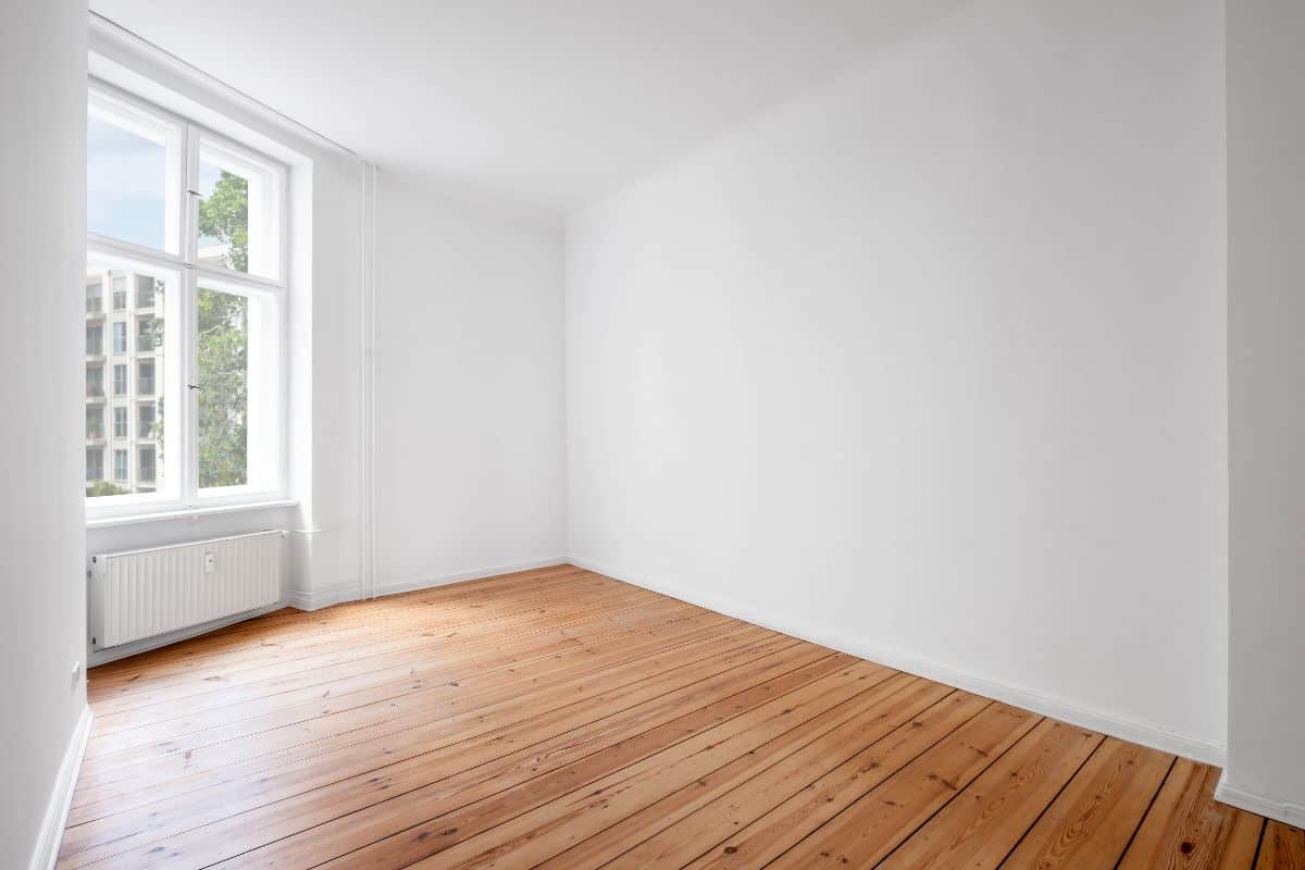 white room in empty flat with window and wooden floor.
