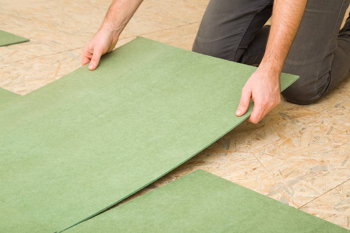 Young adult man hands laying green natural wood fiber insulation board.