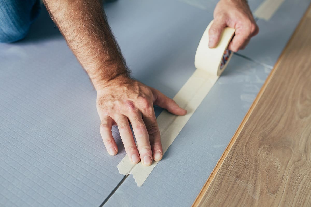 Secure the flooring. - Laminate technician glues backing sheets together - professional flooring