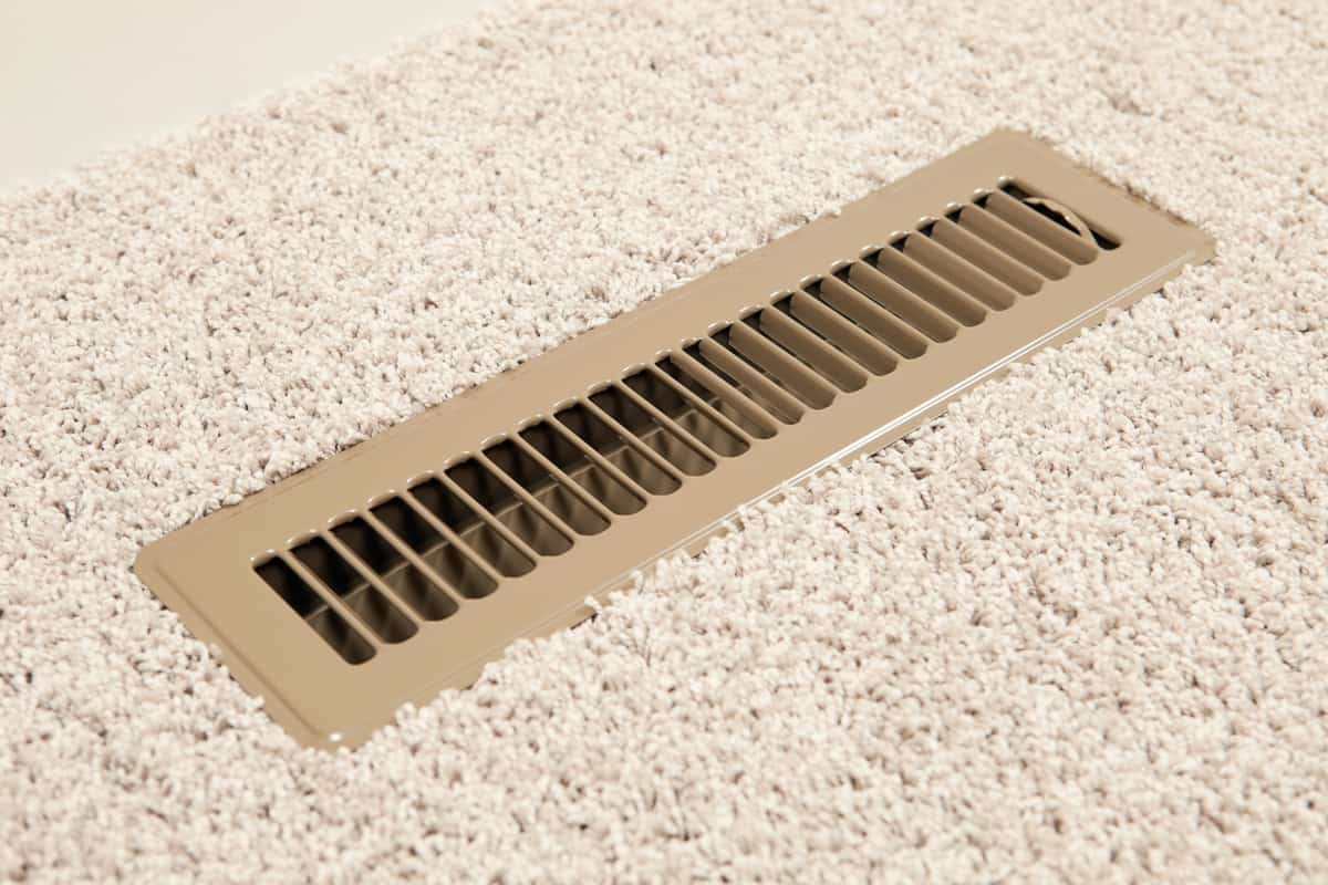 A new metal household adjustable HVAC vent register on a carpeted floor.
