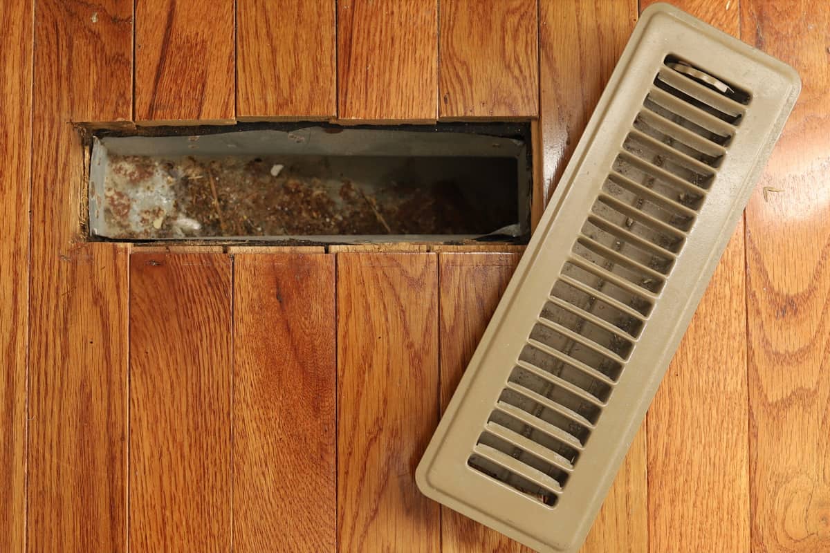 A opened heating/cooling vent register on the floor in a home home.