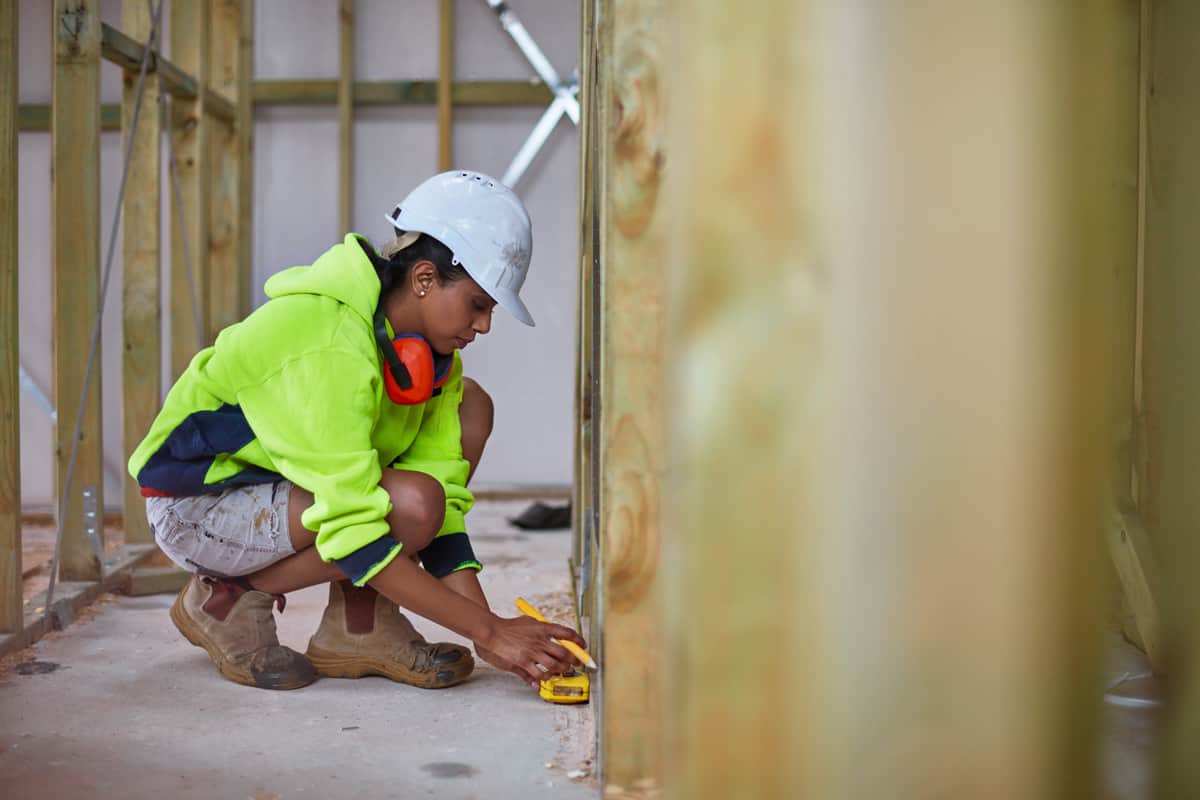 Female worker using tape measure at site.