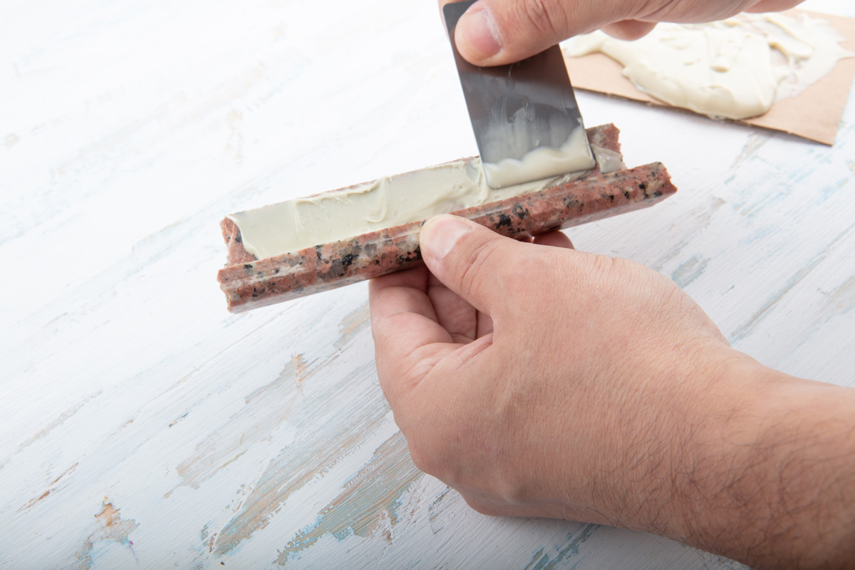 Man using two component adhesive for repairing marble in a close up view of his hands in a concept of DIY repairs with copy space.