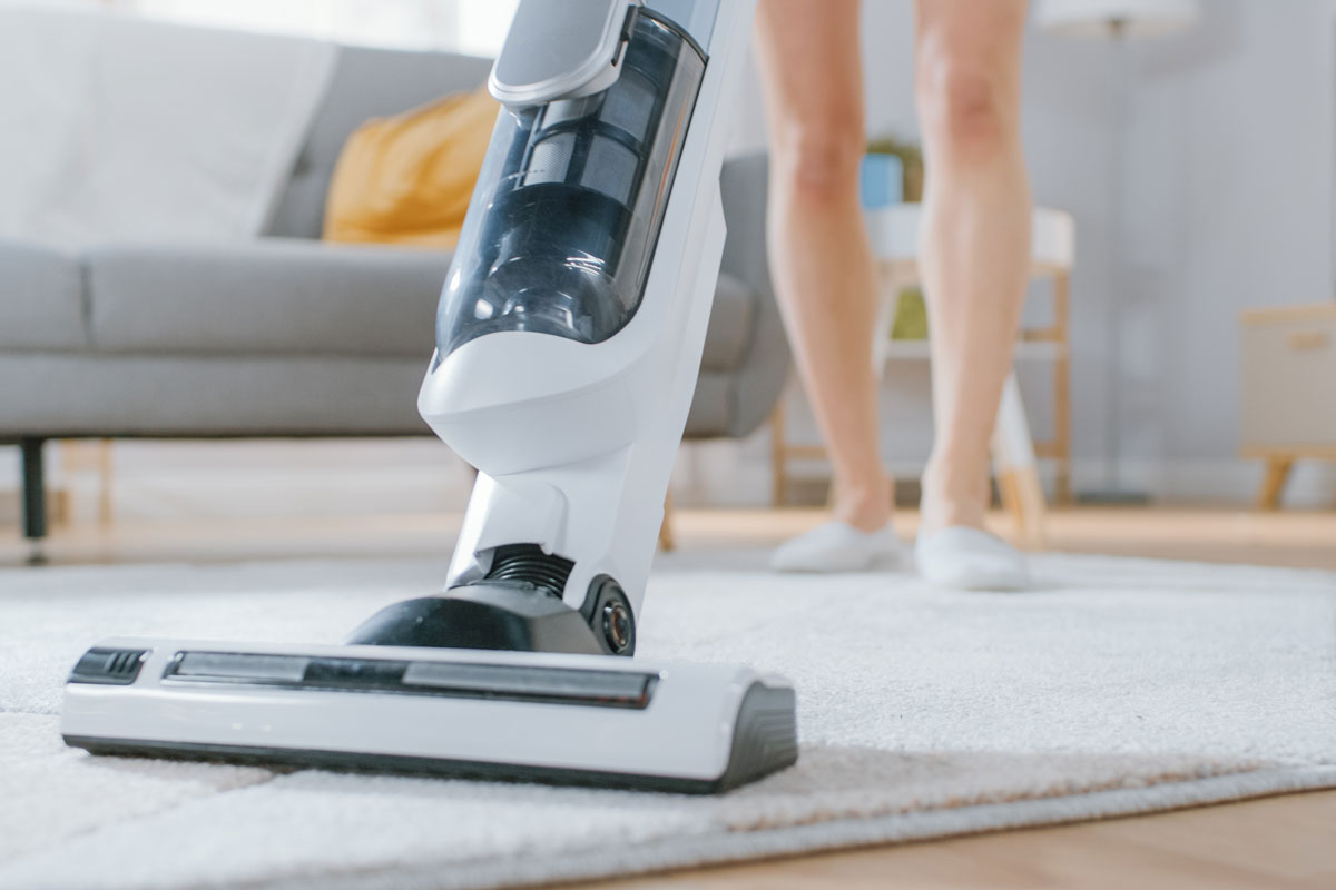 Woman using Electrolux Vacuum cleaning a carpet in a bright cozy room at home
